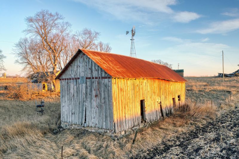Rustic barn with a rusty roof set against a rural Minnesota landscape at sunrise.