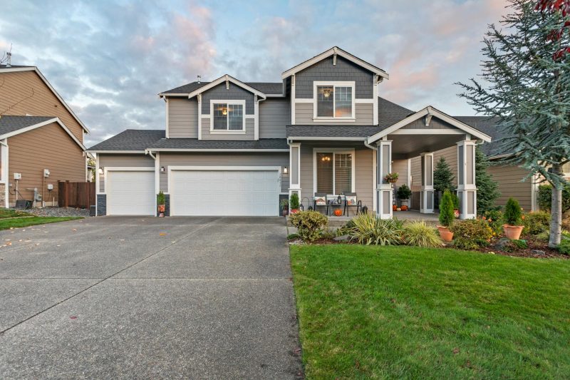 Charming two-story house with a manicured lawn and garage under a dusky sky.