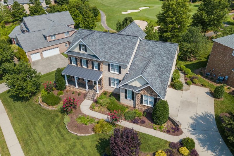 Bird's-eye view of a well-maintained suburban home surrounded by vibrant greenery.