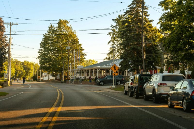 Cozy street view in Holland, Michigan with parked cars, trees, and warm evening light.