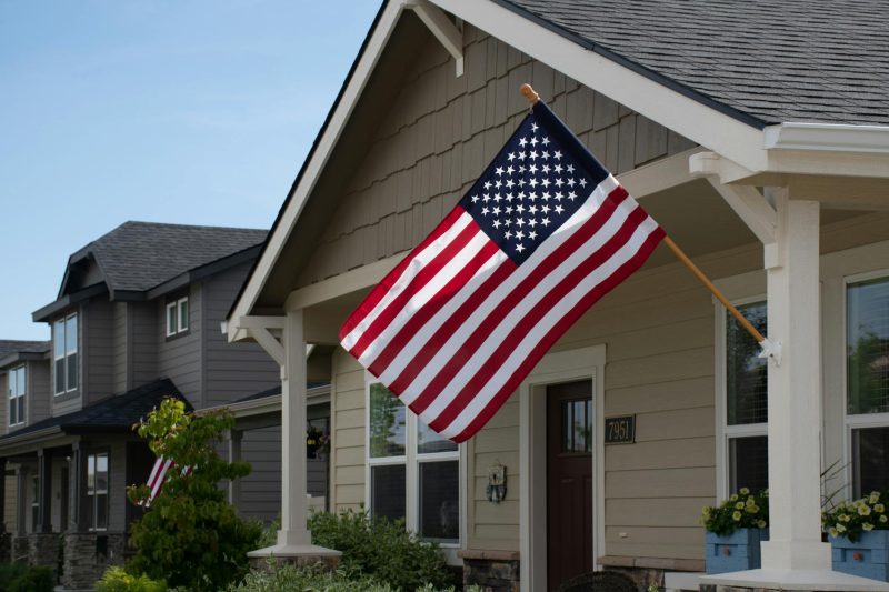 Vibrant American flag hanging outside a stylish suburban house under bright daylight.