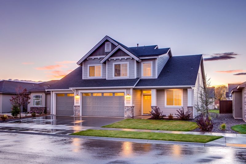 Elegant suburban home with modern architecture and a driveway, illuminated by a warm sunset.