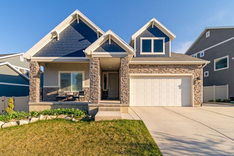 Charming modern suburban home with a stone facade and a well-maintained lawn.