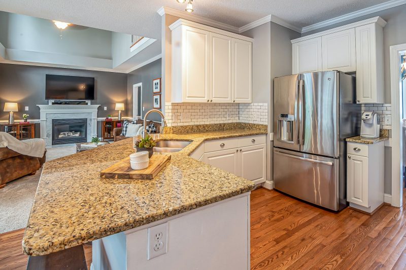 Luxurious open-concept kitchen with granite countertops and modern appliances, leading to a cozy living room with a fireplace.