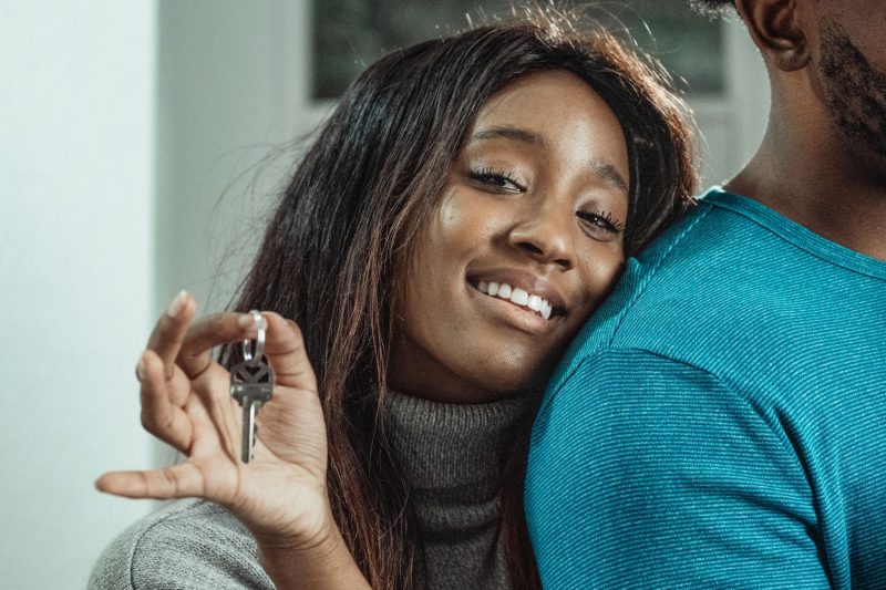 Joyful couple holding house keys, smiling and celebrating their new home purchase.